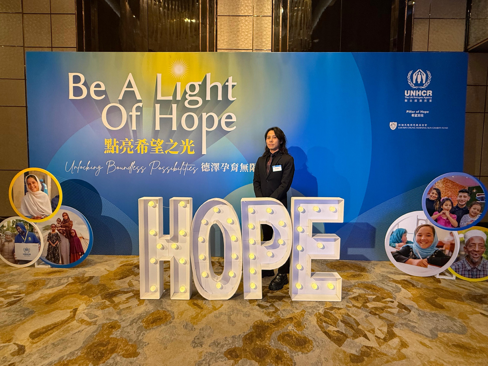 Our representative in front of the backdrop at the UNHCR Gala Dinner 2024 "Be A Light of Hope"